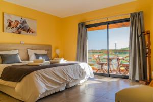 1 dormitorio con cama y ventana grande en Un Alto en la Huella - Hotel Spa & Wellness Resort en San Antonio de Areco
