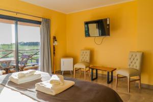 a room with a bed and a tv and a balcony at Un Alto en la Huella - Hotel Spa & Wellness Resort in San Antonio de Areco