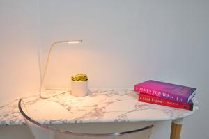 a table with two books and a lamp on it at Appartement standing à 7min de Fontainebleau centre, 3min de Moret-sur-Loing et 45min de Paris (1min à pied de la gare) in Veneux-les-Sablons