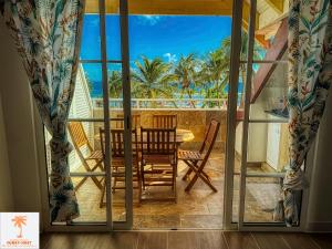 a dining room with a table and chairs on a balcony at Ti Kaz Funky Host -T3 vue mer prémium 3 étoiles - Village vacances Sainte Anne Guadeloupe in Sainte-Anne