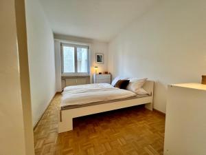 ein weißes Bett in einem Zimmer mit Fenster in der Unterkunft Gemütliche grosse Wohnung Nähe Uni in Basel