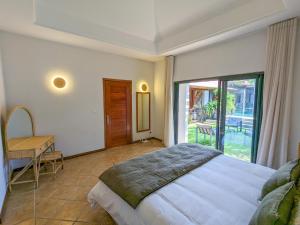 1 dormitorio con cama, mesa y ventana en Plumeria Villa, en Pointe aux Cannoniers
