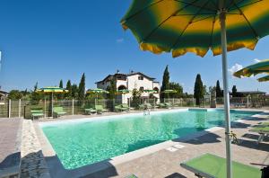 una casa y una piscina con sombrillas y sillas en Agriturismo La Verde Rosa, en Pescia Romana
