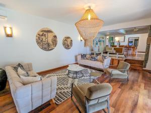 una sala de estar con muebles blancos y una lámpara de araña. en Plumeria Villa, en Pointe aux Cannoniers