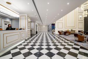 a woman standing at a counter in a lobby with a checkered floor at فندق شراعوه الملكي - Luxury in Doha