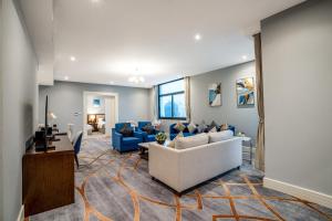 فندق شراعوه الملكي - Luxury في الدوحة: غرفة معيشة مع أريكة بيضاء وكراسي زرقاء