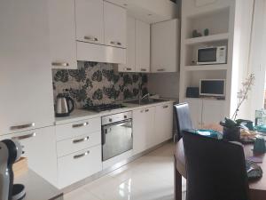 cocina con armarios blancos, mesa y comedor en Civico 37 Casa Vacanze Porta Romana, en Milán