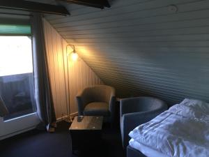 Zimmer mit 2 Stühlen, einem Bett und einem TV in der Unterkunft Harvey`s Bed & Breakfast in Hjørring