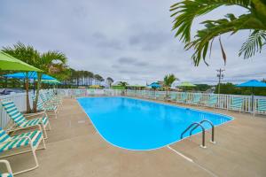 a pool with chairs and umbrellas at a resort at Jellystone Park Chincoteague Island in Chincoteague