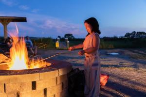 a woman standing next to a fire pit at Jellystone Park Chincoteague Island in Chincoteague