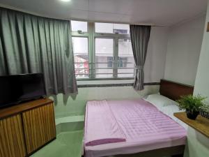 een kleine kamer met een roze bed en een raam bij 香港百乐宾馆 Best-B&B in Hong Kong