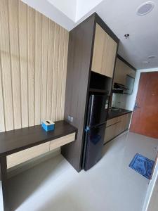 eine Küche mit einem schwarzen Kühlschrank und Holzschränken in der Unterkunft Unit B50-10 Pollux Habibie Luxury in Batam Center