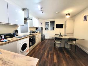 una cocina con armarios blancos y una mesa con sillas. en Guest House - close to all amenities, en Northampton