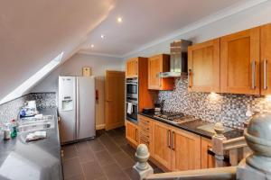 una cucina con armadi in legno e frigorifero bianco di The Gables Penthouse a Poole