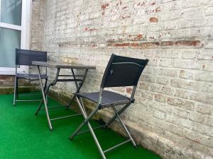 duas cadeiras e uma mesa em frente a uma parede de tijolos em Maison standing 9 chambres 5SB avec extérieur em Roubaix