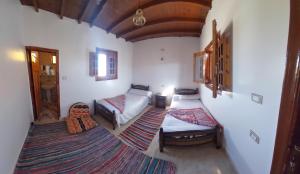 Habitación pequeña con 2 camas y alfombra. en Hayaat siwa hot spring, en Siwa