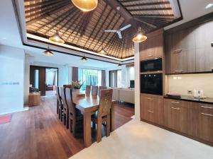 uma cozinha e sala de jantar com uma mesa de madeira e cadeiras em Bali - Jimbaran Bay 2 Bedroom Villa em Jimbaran