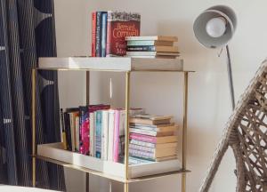 a book shelf filled with books next to a lamp at The Beach Box By Air Premier in Seaford