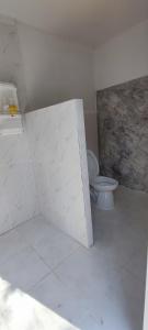 a bathroom with a toilet and a white wall at Khanchong kawana in Phitsanulok