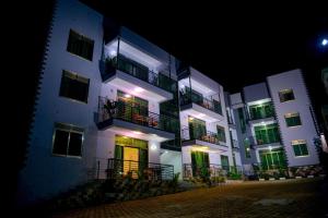 a large white building with green doors and balconies at night at 2 Bedroom Suite In 3 Bedroom Apartment in Namulanda