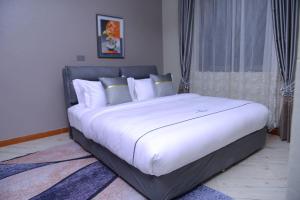 - une chambre avec un grand lit et des draps blancs dans l'établissement 2 Bedroom Suite In 3 Bedroom Apartment, à Namulanda