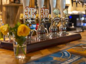 a bar with glasses and flowers on a table at Priory Inn in Tetbury