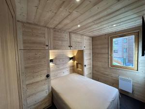małą sypialnię z łóżkiem w drewnianej ścianie w obiekcie Appartement Méribel, 4 pièces, 8 personnes - FR-1-180-173 w Méribel
