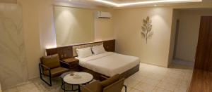 Arica hotel apartments في تبوك: غرفه فندقيه بسرير وكرسي وطاولة