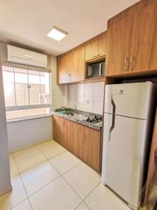 uma cozinha com um frigorífico branco e armários de madeira em AP ap aps em São João del Rei