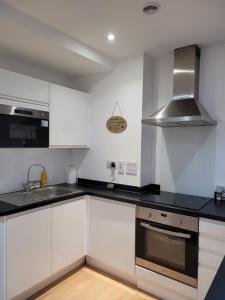 a kitchen with white cabinets and black counter tops at Amazing Canterbury 1 BR Flat in London CB54 in Croydon