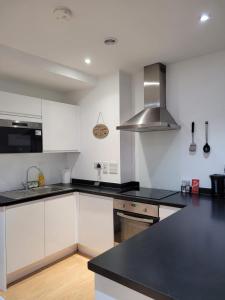 a kitchen with white cabinets and a black counter top at Amazing Canterbury 1 BR Flat in London CB54 in Croydon