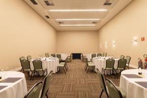 uma sala de banquetes com mesas e cadeiras brancas em Golden Tulip São José dos Campos em São José dos Campos