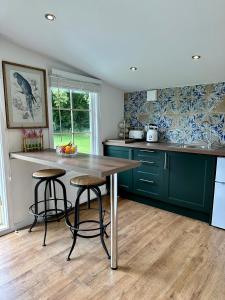 a kitchen with green cabinets and a wooden table and stools at Oak View Lodge: Cosy, Countryside Retreat in Maybole
