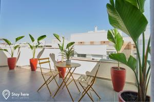 balcone con piante in vaso, tavolo e sedie di Stayhere Rabat - Agdal 4 - Hotel a Rabat