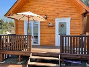 a wooden cabin with an umbrella on the porch at Biwako Hills Resort - Vacation STAY 99556v in Takashima