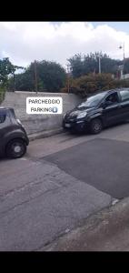 dos autos estacionados en un estacionamiento con un cartel en Monolocale Palermo torretta, en Torretta