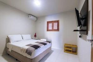 - une chambre avec un lit et une télévision dans l'établissement Condomínio aconchegante a 300mt da Praia de Barra Grande, à Barra Grande