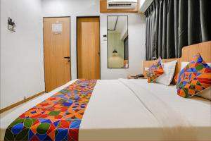 een slaapkamer met een groot bed en een kleurrijke deken bij FabHotel Saarthi Inn in Surat