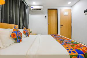 蘇拉特的住宿－FabHotel Saarthi Inn，卧室配有一张带彩色枕头的大型白色床。