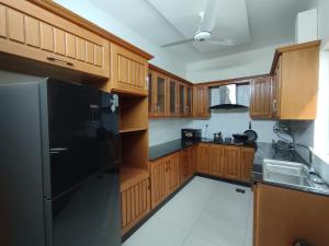 a kitchen with wooden cabinets and a black refrigerator at Luxury Holiday Home in Islamabad in Islamabad