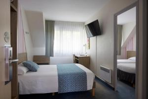 a hotel room with two beds and a flat screen tv at The Originals City, Hôtel Les Océanes, Lorient in Lorient