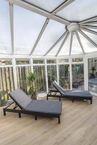 Duas camas num jardim de Inverno com janelas em Oasis Retreat Hot Tub Cupar em Cupar