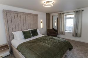 a bedroom with a bed and a chair and a window at Oasis Retreat Hot Tub Cupar in Cupar