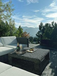 a patio with a couch and a table with a bottle of wine at Das Himmelhaus Sot il Pegn in Lenzerheide