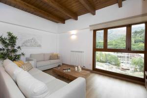 sala de estar con sofá blanco y ventana grande en Sueños del Garmo by BeValle, en Panticosa