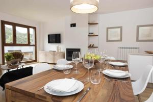 a dining room with a wooden table with plates and wine glasses at Casa Mia by BeValle in Panticosa