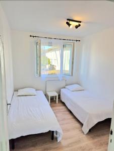 two beds in a white room with a window at Maison à Aurillac - 3 chambres - Arrivée autonome in Aurillac
