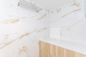 baño con paredes de mármol blanco y espejo en Studio1 Van Lerius, en Amberes