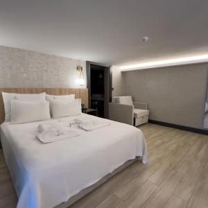 a bedroom with a large white bed and a chair at CUNDA PİER OTEL in Ayvalık +39 photos