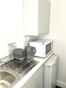 a kitchen counter with a microwave and a sink at Hyland Apartment by CityNest in Chelmsford